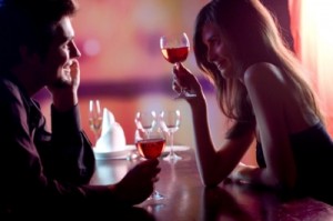 Young couple sharing a glass of red wine in restaurant, celebrating or on romantic date