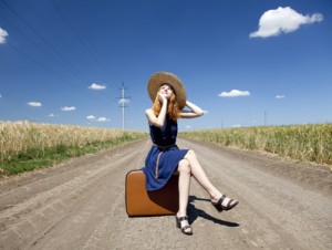 Lonely girl with suitcase at country road.